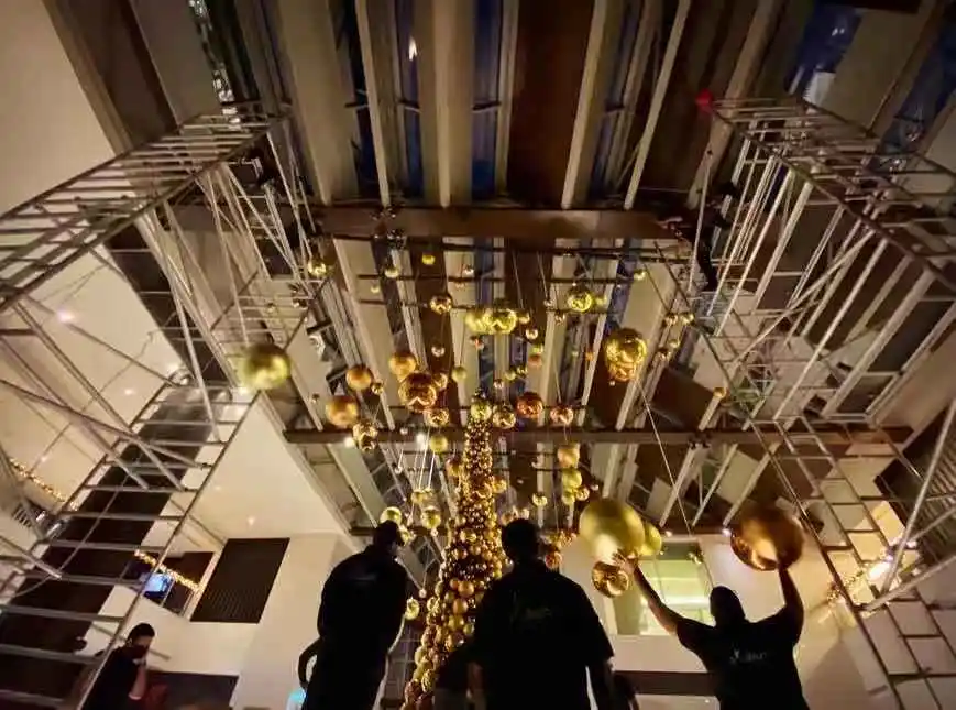 Professional Christmas decor setup with golden hanging ornaments and festive tree design.