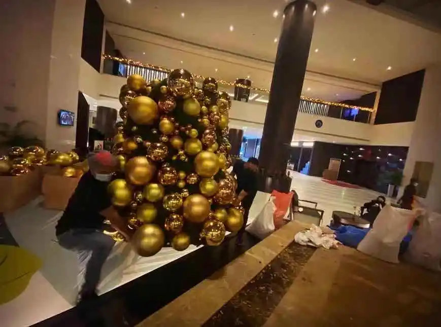 Order grand lobby Christmas decor featuring tall golden tree and ceiling ornaments.