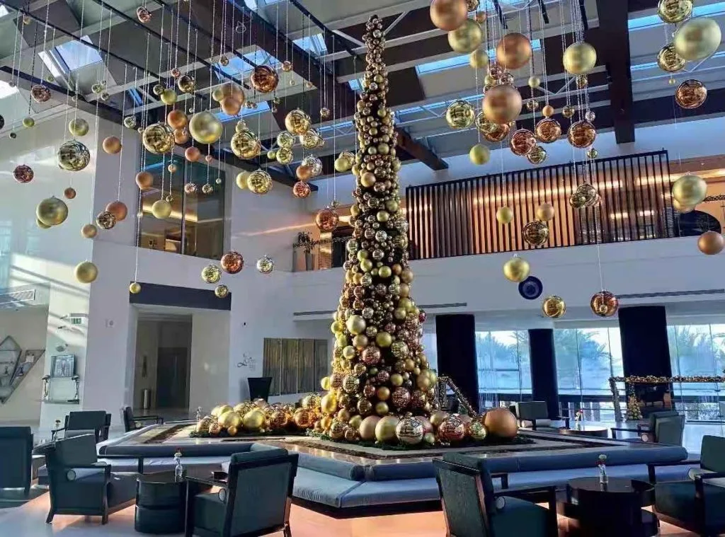 Elegant Christmas decor display with golden bauble tree centerpiece and suspended ornaments.