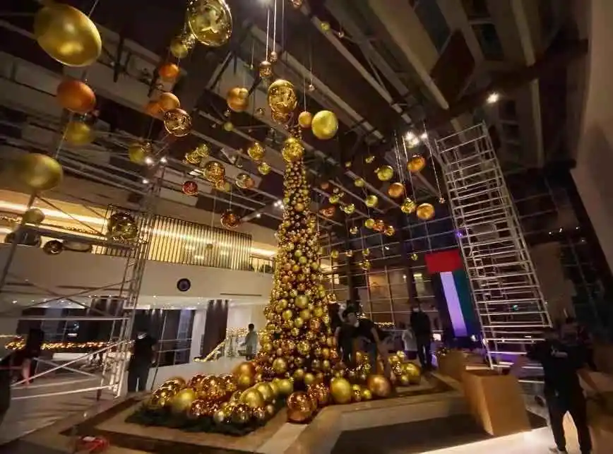 Luxury hotel Christmas decor with golden bauble tree and hanging ornaments installation.