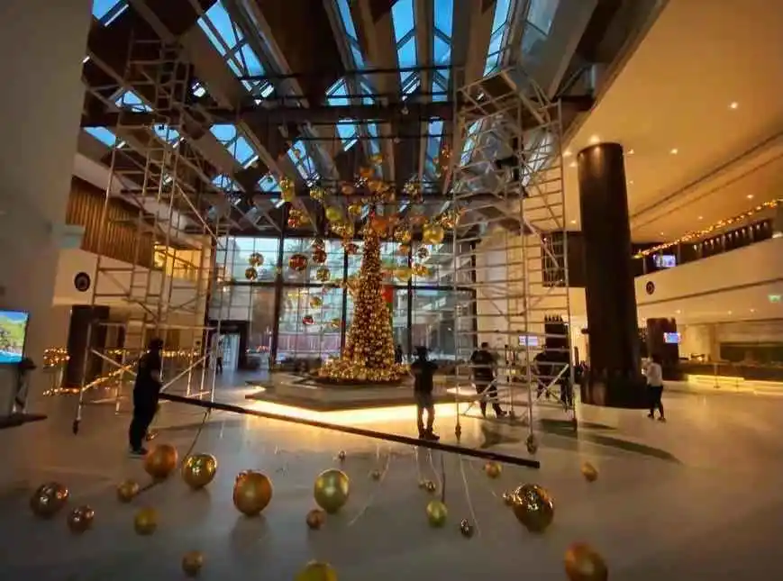 Custom Christmas decor installation with gold ornaments for luxury hotel interiors.